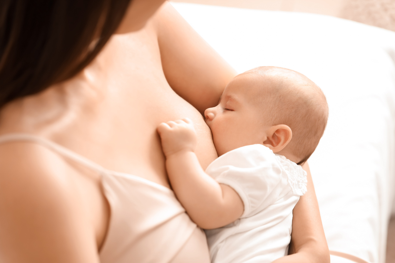 Young Woman Breastfeeding Her Baby in Bedroom, Closeup
